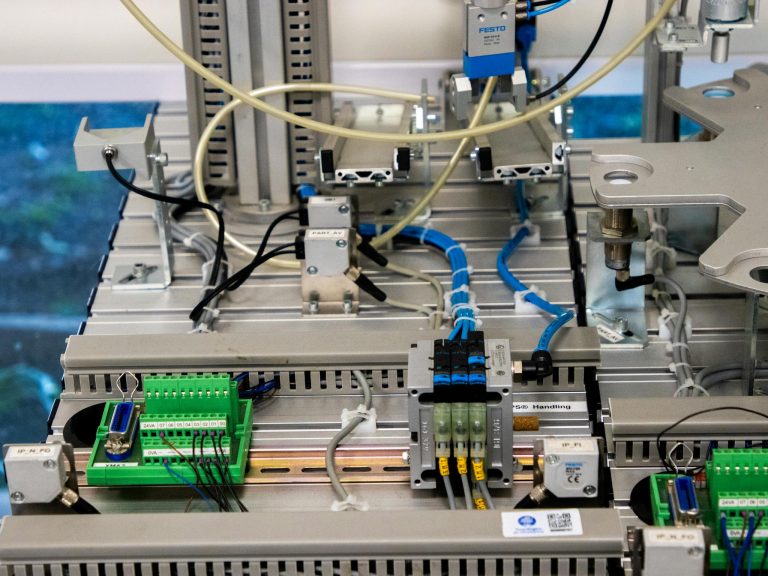 Close-up of industrial equipment showcasing electronic wiring and sensors in a manufacturing setup.